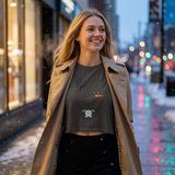 “Woman wearing the Pepper cropped T-shirt with tree, snowman face and teddy bear design under a tan coat.”